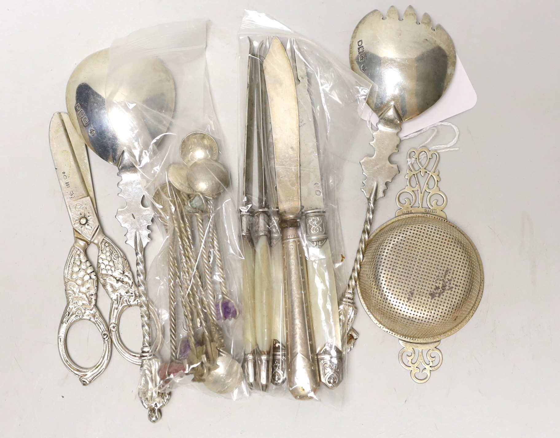 Small silver including a pair of late Victorian servers, by William Hutton & Sons, 830 standard white metal grape shears, tea strainer, fruit knives and novelty coin spoons and forks.